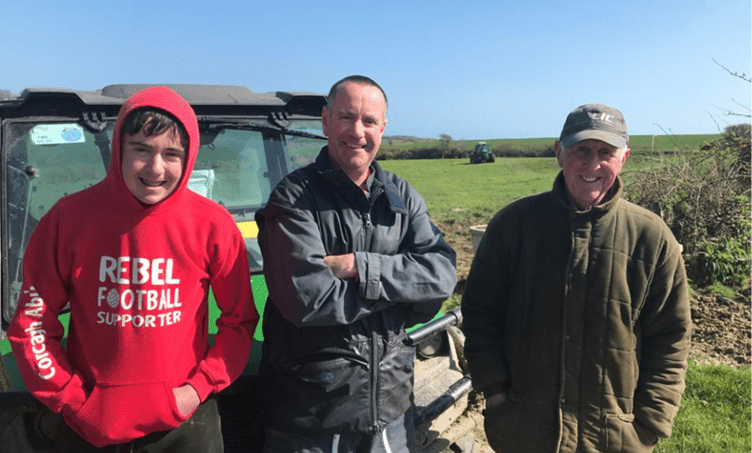Denis O'Donovan, his son Eoghan and his father DJ standing beside a farm vehicle on their dairy farm in West Cork.